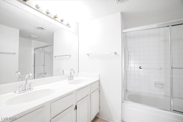 bathroom featuring bath / shower combo with glass door, visible vents, a sink, and double vanity