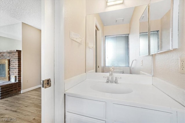 bathroom featuring a textured ceiling, wood finished floors, vanity, and baseboards