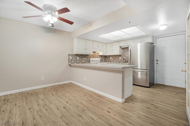 kitchen featuring light wood finished floors, light countertops, freestanding refrigerator, range, and a peninsula