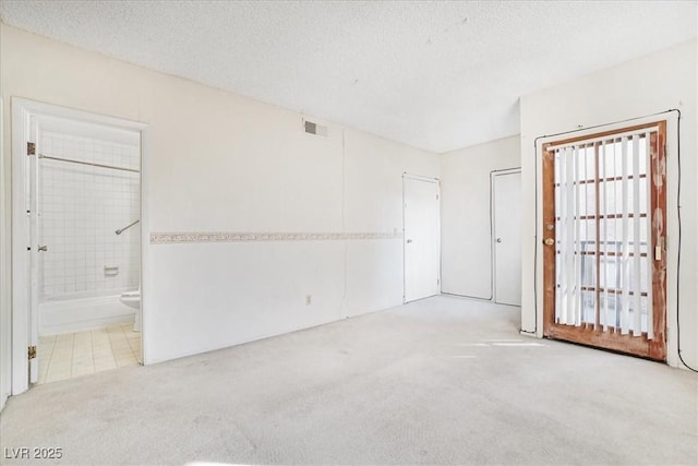 empty room featuring visible vents, a textured ceiling, and carpet flooring