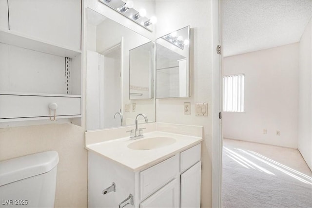 bathroom featuring toilet, a textured ceiling, and vanity