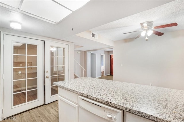 kitchen with visible vents, dishwasher, a textured ceiling, french doors, and light wood-style floors