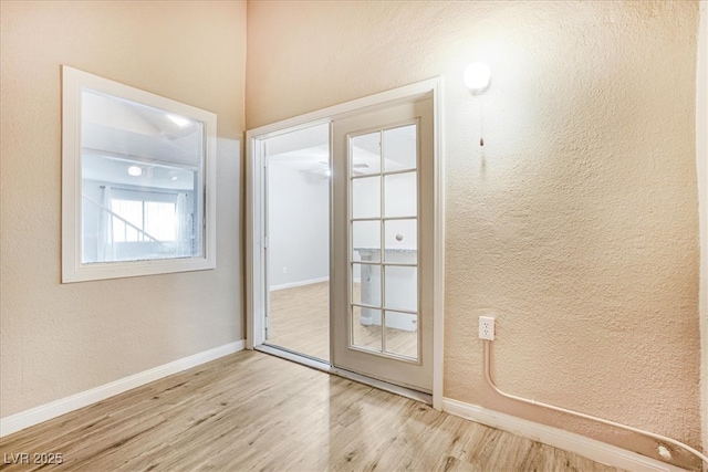 doorway to outside with baseboards, wood finished floors, and a textured wall