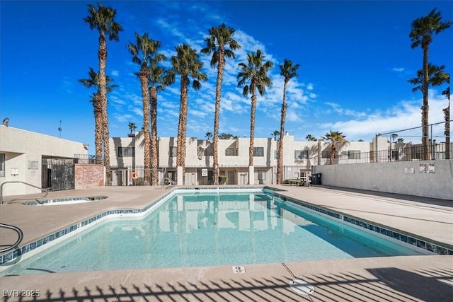 pool with a residential view, a patio area, fence, and a hot tub