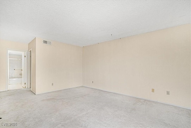 spare room with visible vents, a textured ceiling, and light colored carpet