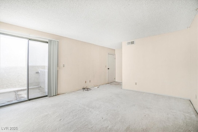 carpeted spare room featuring visible vents and a textured ceiling