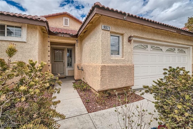 property entrance with a tiled roof, stucco siding, and an attached garage