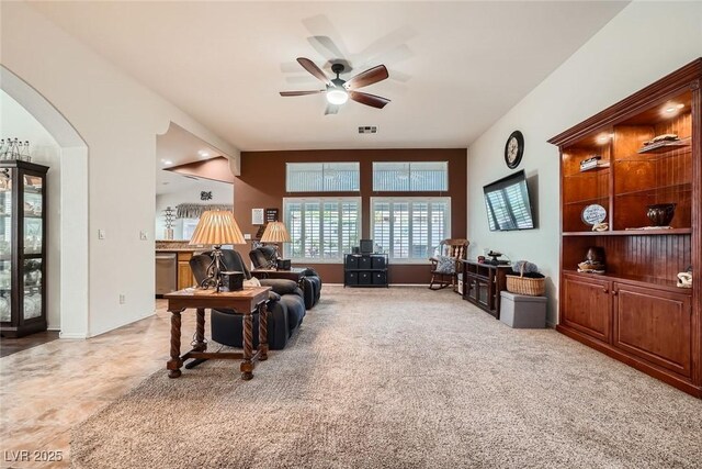 living area with visible vents, light carpet, arched walkways, and a ceiling fan