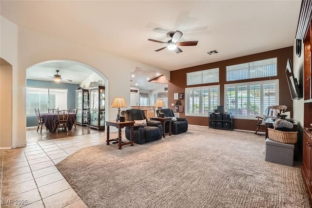 living area with arched walkways, visible vents, plenty of natural light, and a ceiling fan