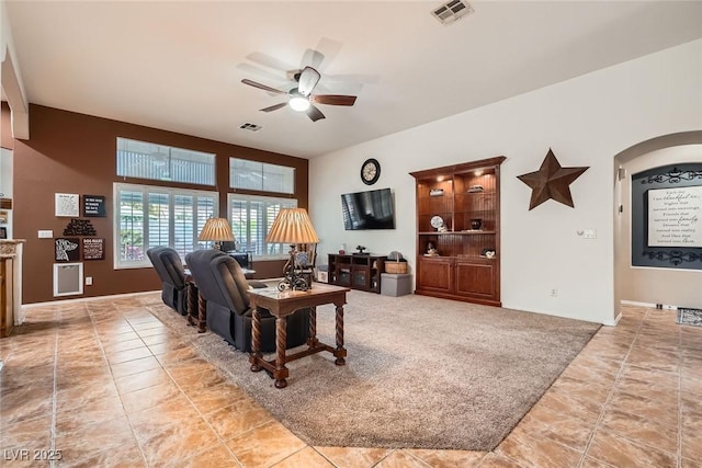 living area featuring visible vents, arched walkways, ceiling fan, and light tile patterned flooring