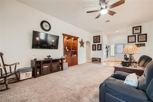 living room with visible vents, carpet floors, arched walkways, and a ceiling fan