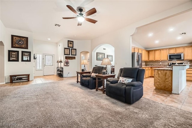 living room featuring light tile patterned flooring, light colored carpet, visible vents, and arched walkways