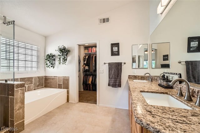 full bath featuring a sink, visible vents, a bath, and double vanity