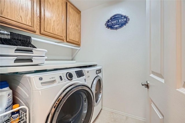 clothes washing area featuring washer and dryer, baseboards, cabinet space, and light tile patterned floors