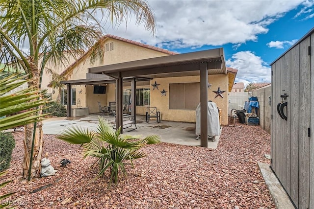 rear view of house with stucco siding, fence, and a patio area