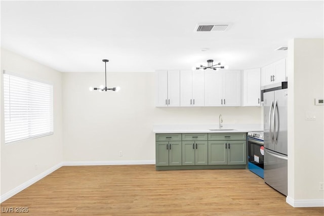 kitchen with visible vents, green cabinetry, appliances with stainless steel finishes, an inviting chandelier, and a sink