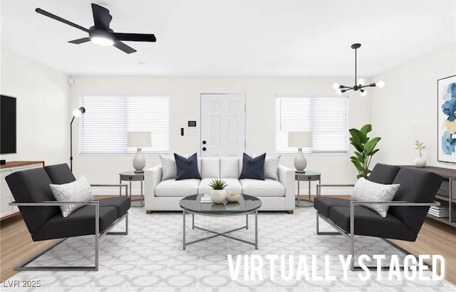 living room featuring ceiling fan with notable chandelier and light wood finished floors