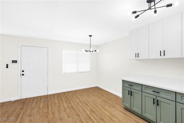 unfurnished dining area with a chandelier, light wood-type flooring, and baseboards