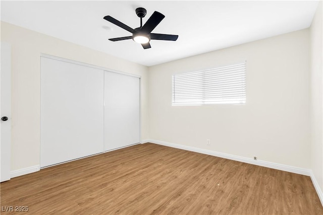 unfurnished bedroom featuring light wood-type flooring, a ceiling fan, baseboards, and a closet