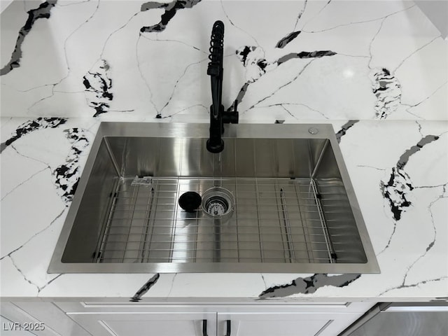 interior details with a sink and light stone countertops