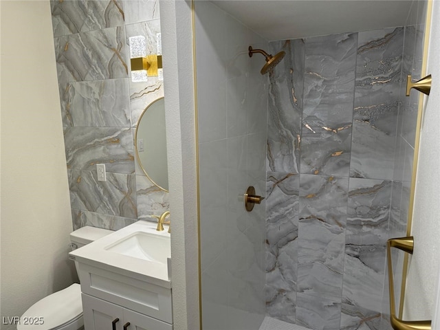 bathroom with toilet, tiled shower, and vanity