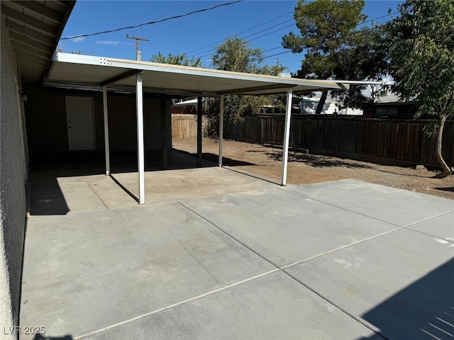 view of patio with fence, an attached carport, and concrete driveway