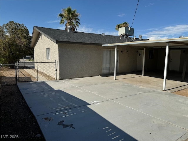 back of house featuring central AC unit, roof with shingles, a gate, fence, and stucco siding