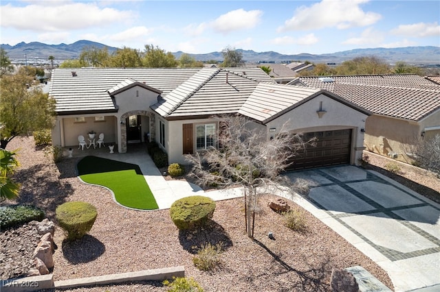 back of property with a garage, concrete driveway, a tile roof, and a mountain view