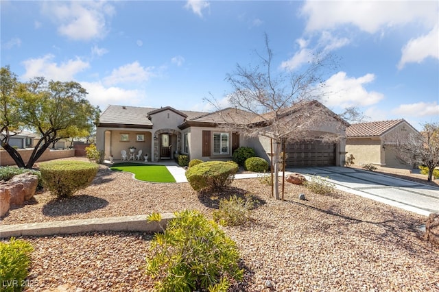 view of front of property with concrete driveway, fence, an attached garage, and stucco siding