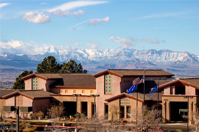 rear view of property with a tile roof, a mountain view, and stucco siding