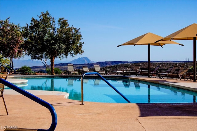 community pool with a mountain view and a patio