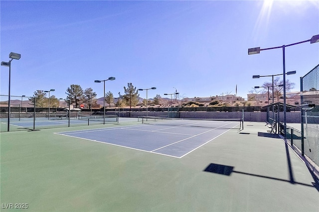 view of tennis court with community basketball court and fence