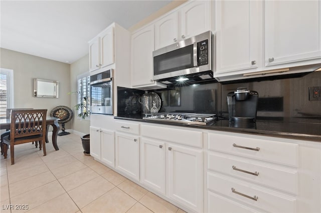 kitchen featuring light tile patterned floors, appliances with stainless steel finishes, backsplash, a wealth of natural light, and dark countertops