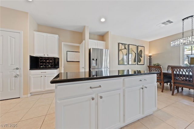 kitchen featuring dark countertops, stainless steel fridge, visible vents, and light tile patterned floors