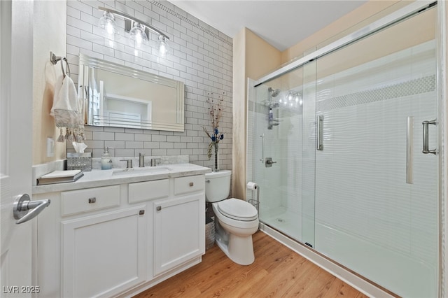 bathroom with a stall shower, tile walls, toilet, and wood finished floors