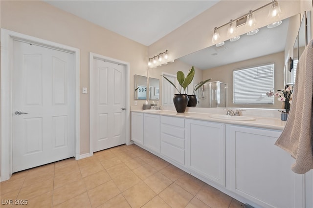 bathroom with tile patterned flooring, a sink, a shower stall, and double vanity