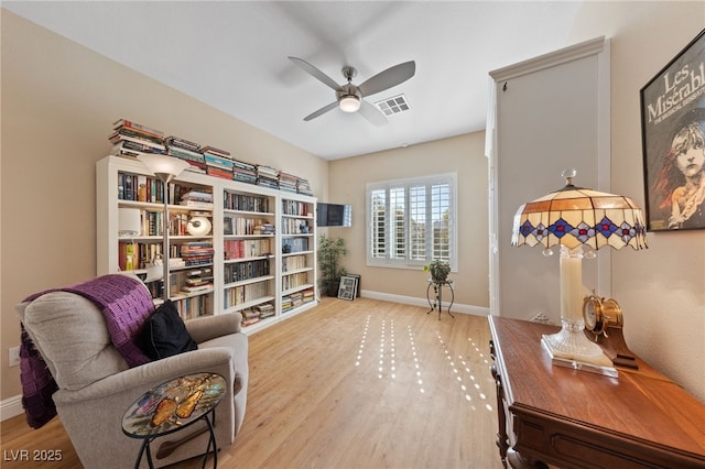 sitting room with a ceiling fan, baseboards, visible vents, and wood finished floors