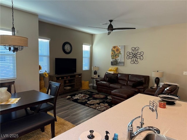 living area with a ceiling fan, visible vents, and wood finished floors