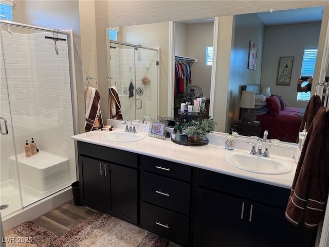 bathroom with connected bathroom, a stall shower, a sink, and double vanity