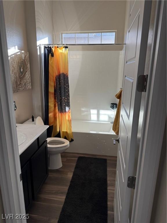 full bath featuring toilet, vanity, wood finished floors, and shower / tub combo with curtain