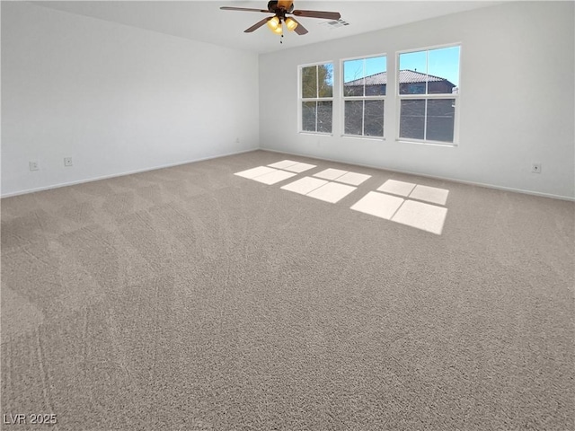 empty room with baseboards, carpet flooring, visible vents, and a ceiling fan