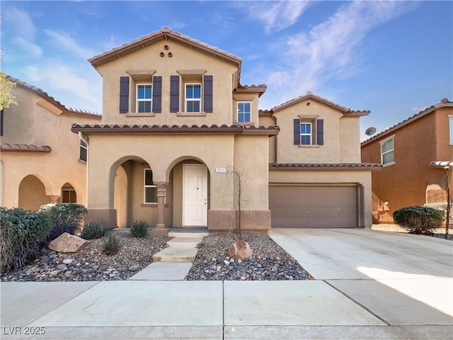 mediterranean / spanish home with a garage, concrete driveway, a tile roof, and stucco siding