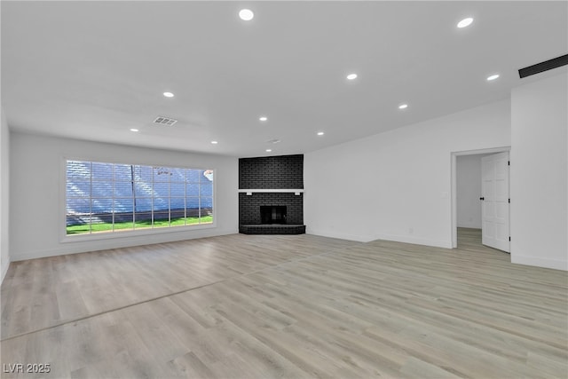 unfurnished living room with visible vents, baseboards, light wood-style flooring, a brick fireplace, and recessed lighting