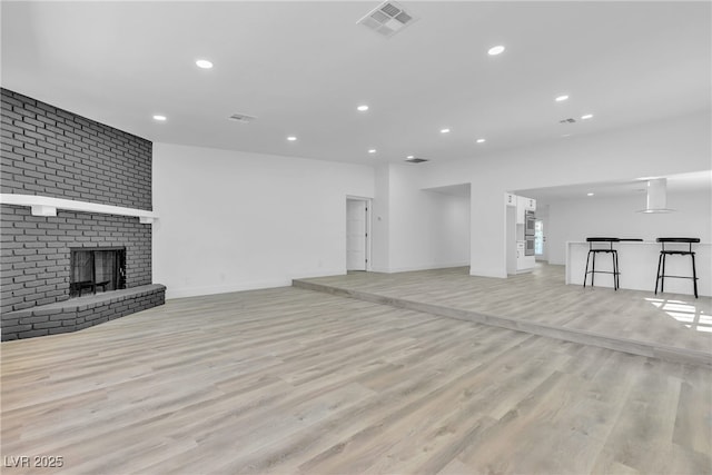 unfurnished living room with a fireplace, recessed lighting, visible vents, light wood-type flooring, and baseboards