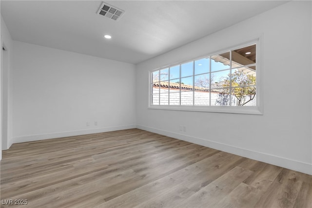 empty room featuring light wood-type flooring, baseboards, and visible vents