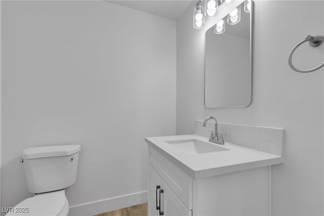 bathroom with toilet, baseboards, wood finished floors, and vanity