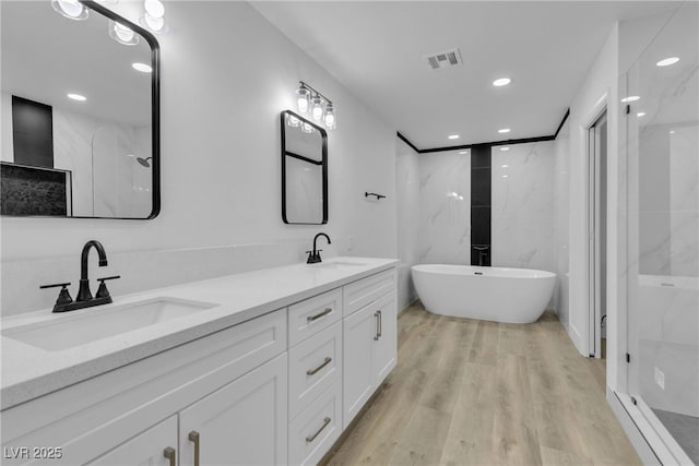 bathroom with double vanity, wood finished floors, a sink, and visible vents