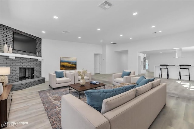 living room featuring recessed lighting, visible vents, a fireplace, and wood finished floors