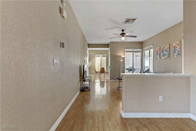 kitchen featuring a ceiling fan, visible vents, baseboards, and wood finished floors