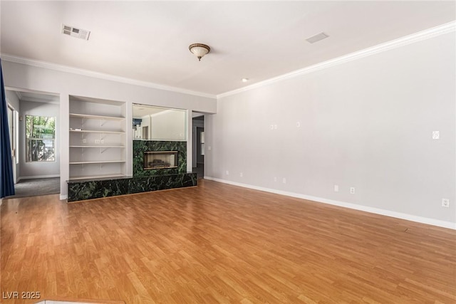 unfurnished living room featuring baseboards, light wood-type flooring, a fireplace, and built in features